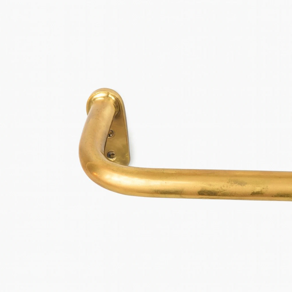 Unlacquered brass curtain rod on a clean white background showing natural patina and warm tone.