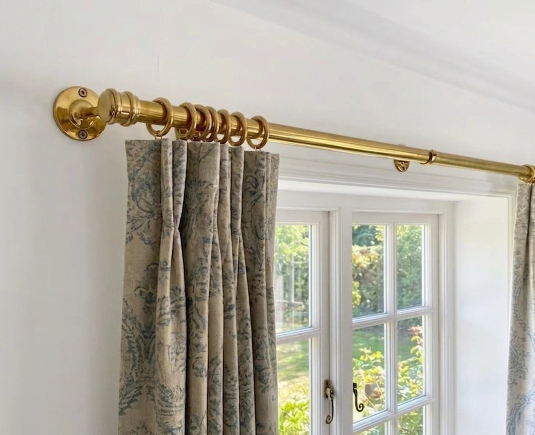 Curtains with a gold curtain rod on a white wall