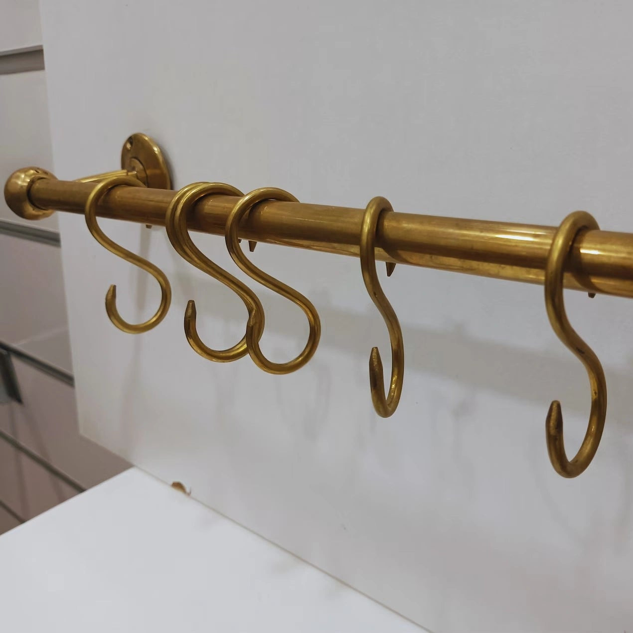 Solid unlacquered brass kitchen rail with S-hooks for hanging pots, pans, and utensils – handmade storage solution from Atlas Finest