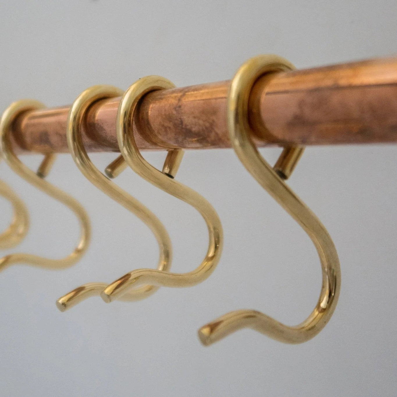 Close-up of brass S-hooks on unlacquered brass and copper kitchen rod – Atlas Finest