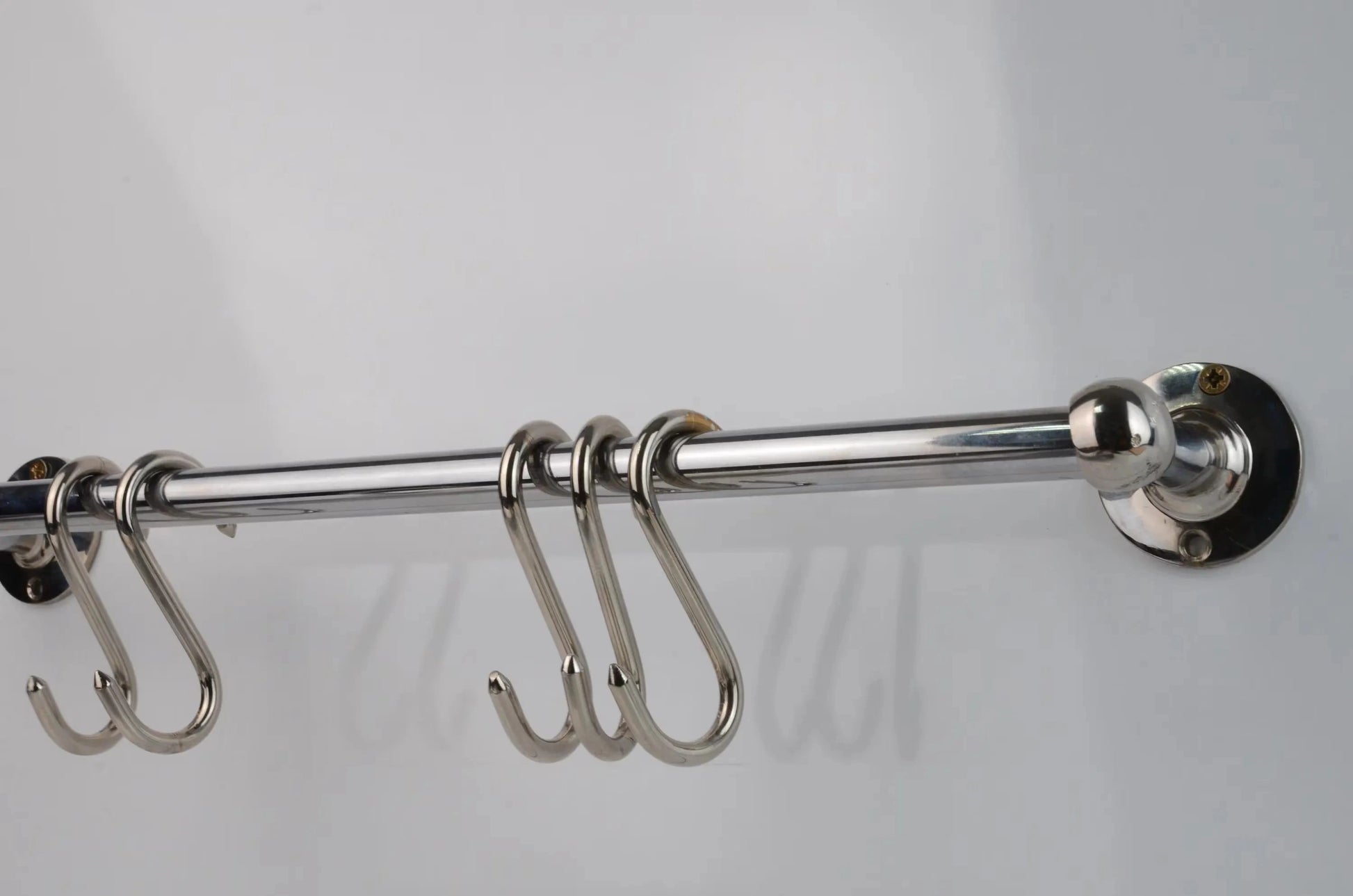 Polished chrome wall-mounted pot rail bar made from solid brass, featuring four S-hooks for kitchen utensil hanging and cookware display