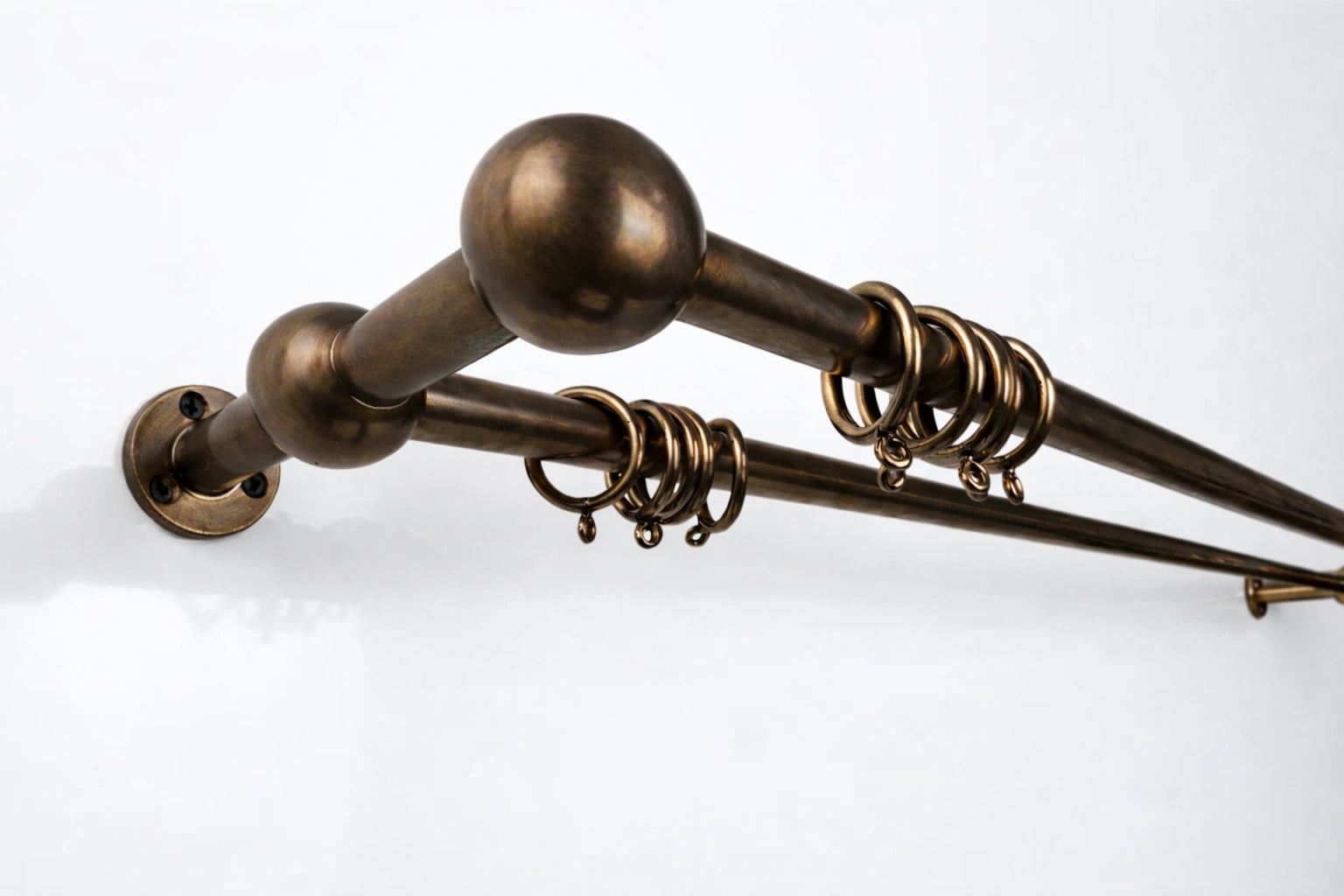 Bronze curtain rod with spherical finials on a white background