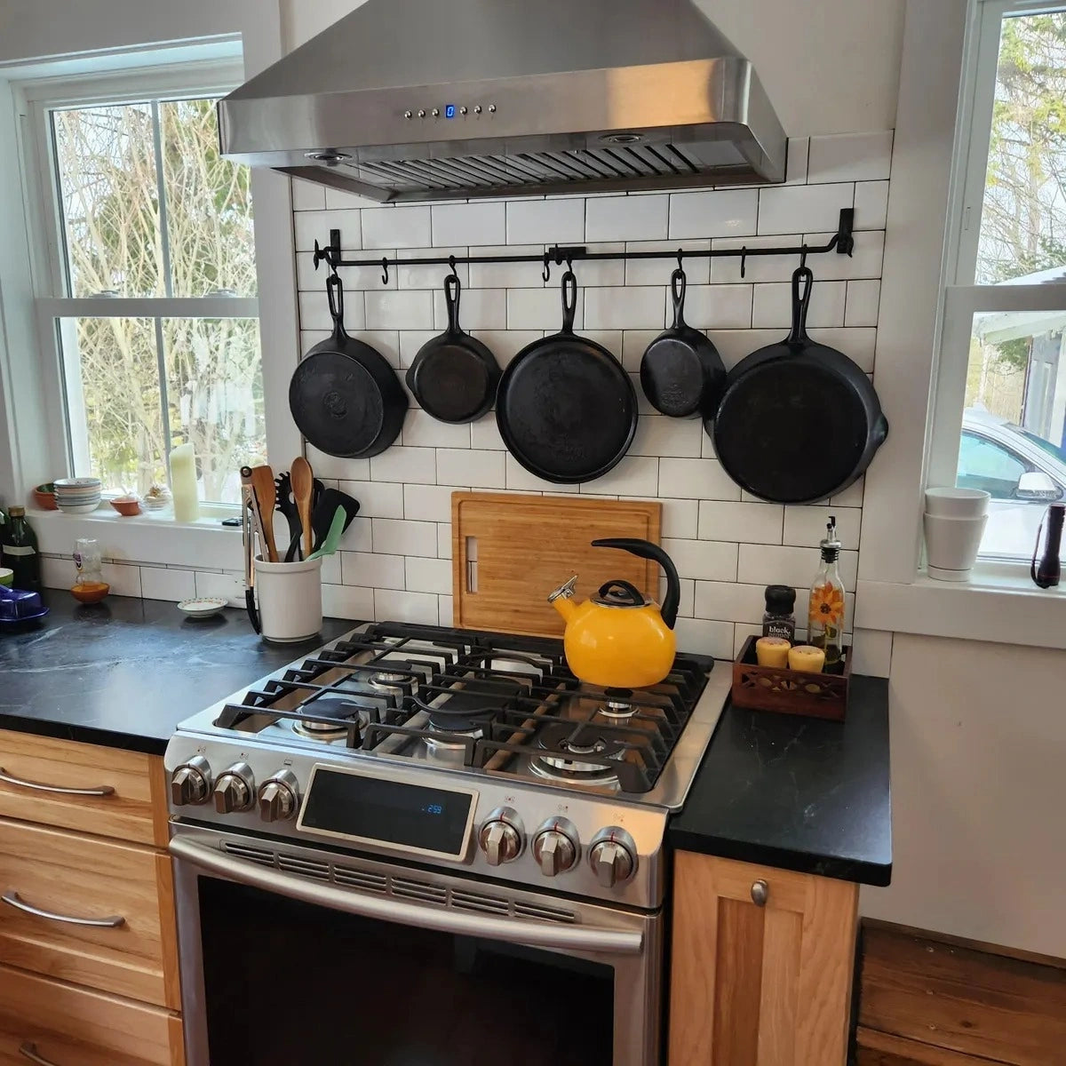 Black forged iron wall-mounted pot rack with hanging cast iron pans in kitchen – Atlas Finest
