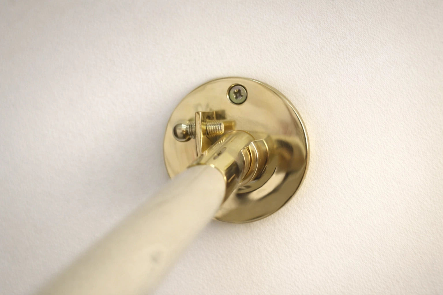 Brass curtain rod bracket on a white wall