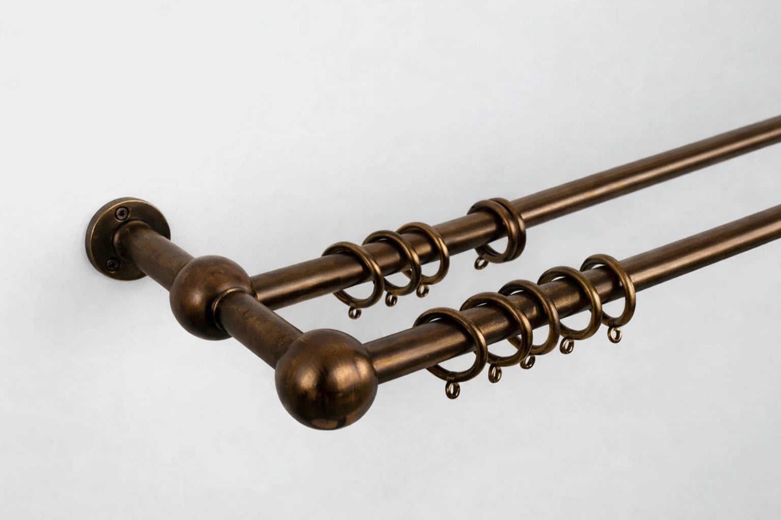 Bronze curtain rod with decorative rings on a white background