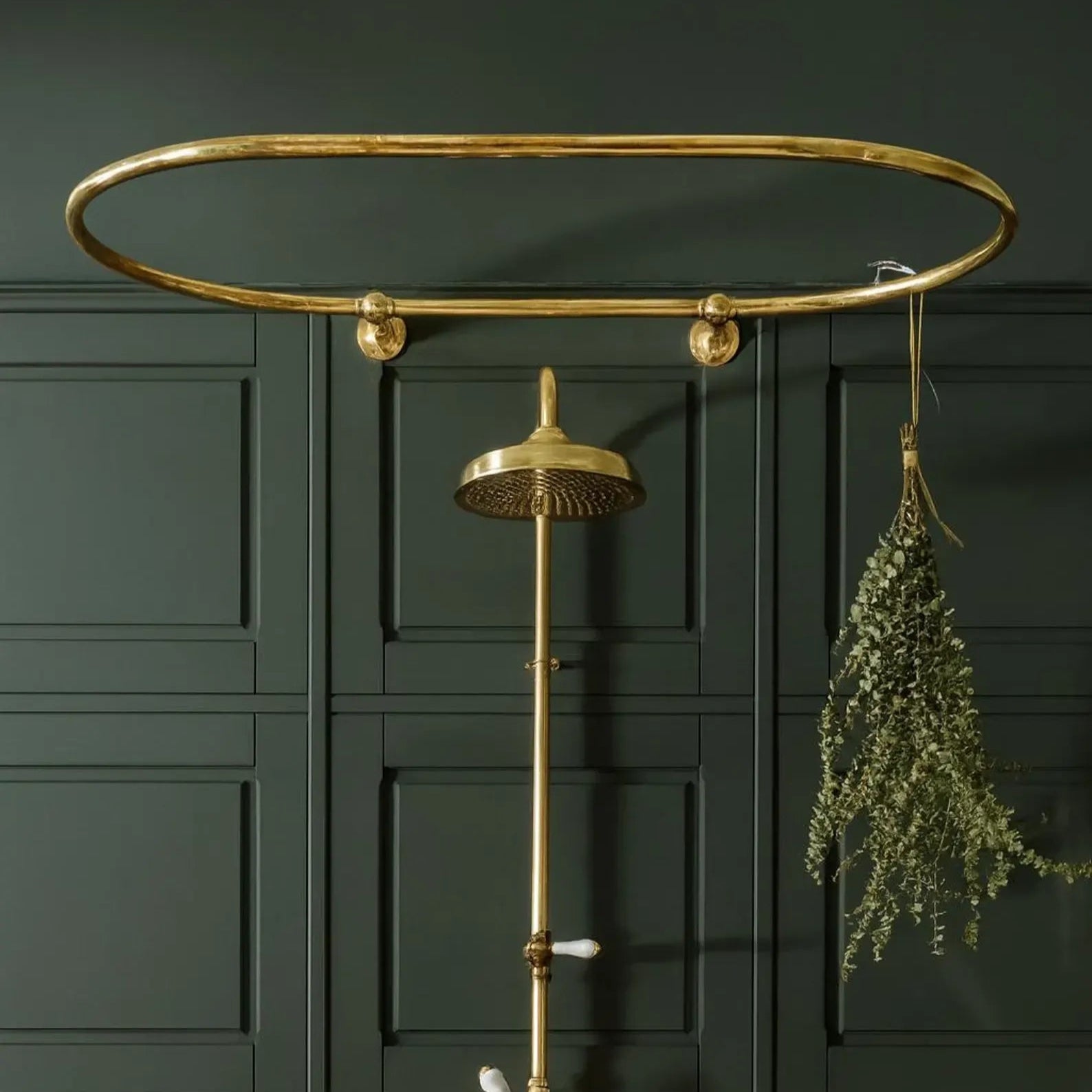 Unlacquered brass shower curtain rod with overhead rain shower and dark green bathroom wall