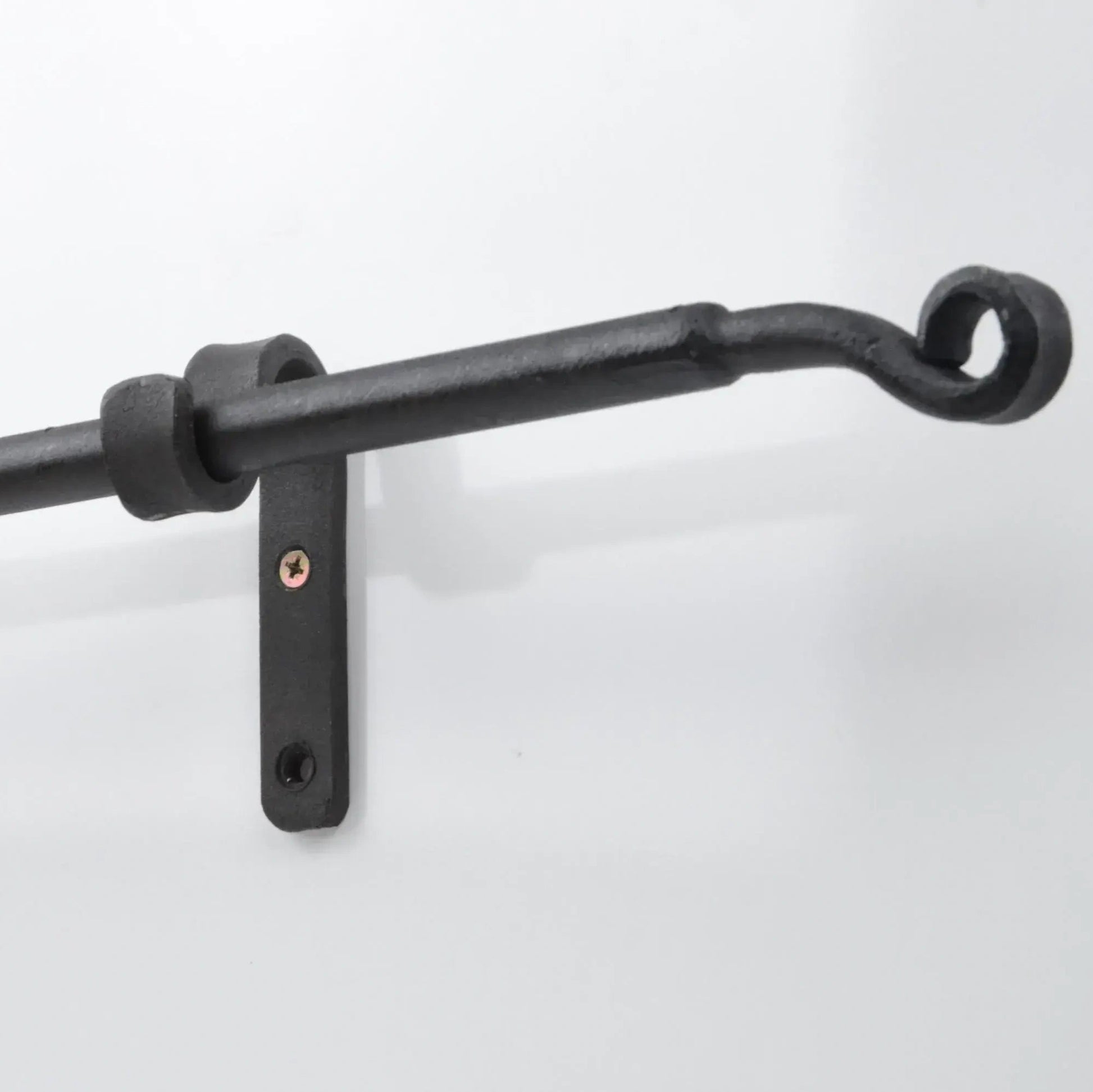 Black wrought iron curtain rod with wall bracket