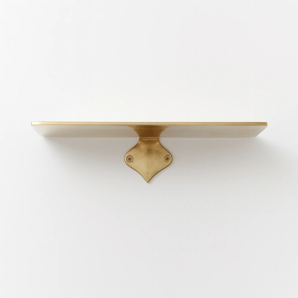 Elegant long unlacquered brass floating shelf mounted on white wall with decorative brass bracket and polished finish