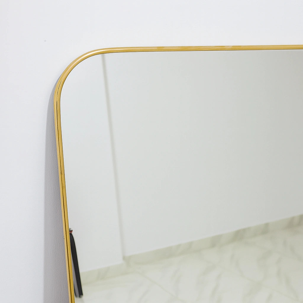 Close-up view of a brass mirror with an unlacquered brass frame, highlighting fine craftsmanship and elegant detailing