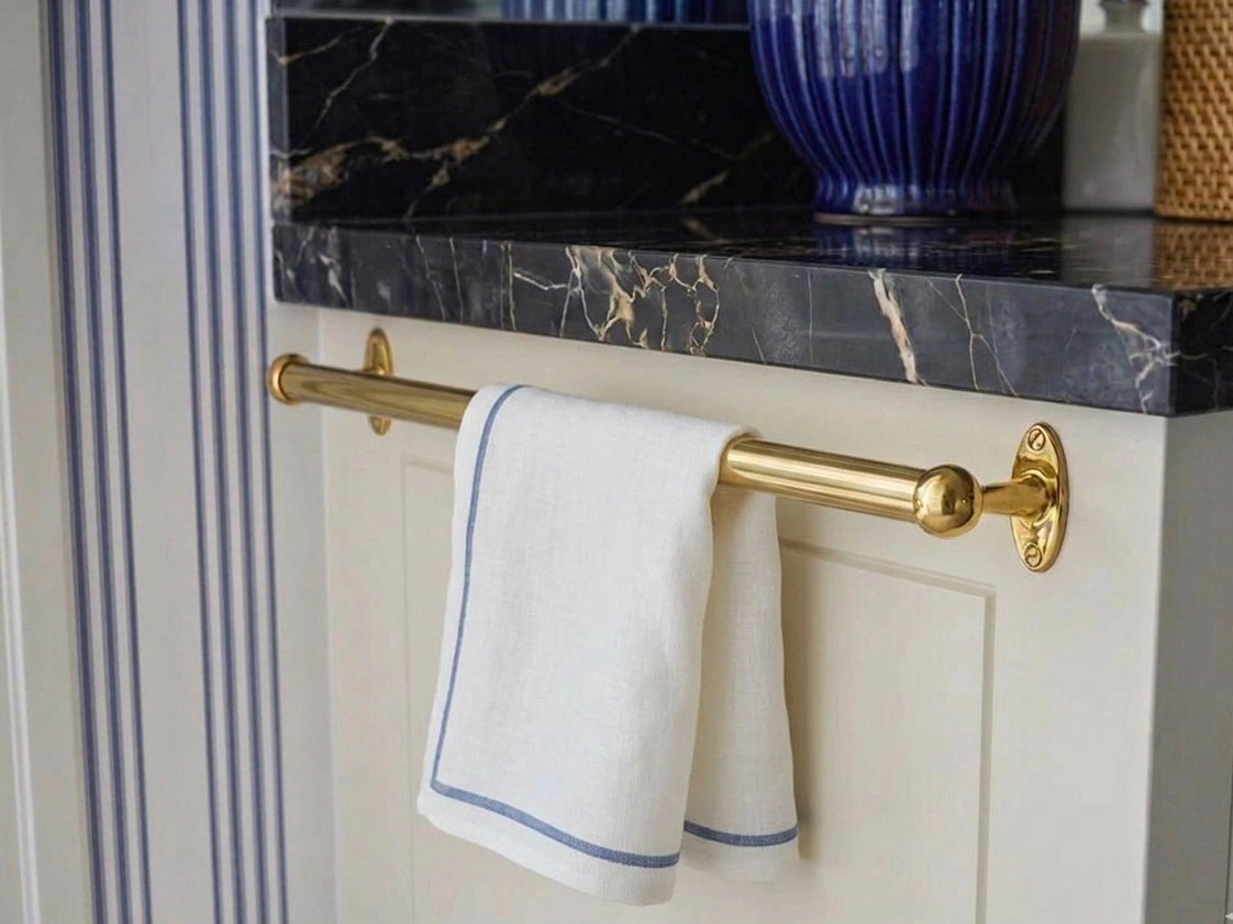 Gold towel rack with a white towel on a marble countertop
